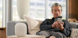 A man sitting on the couch with a Nest Wi-Fi router in front of him.