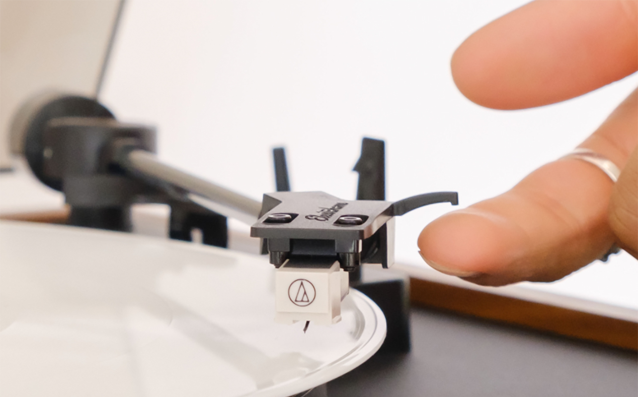 A finger on the stylus of the Electrohome Montrose Audio Technica turntable.