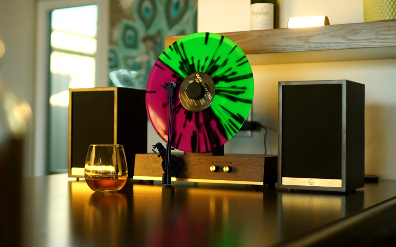 A Fuse vertical gold record player with two speakers and wine.