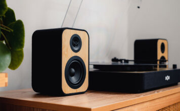 House of Marley Stir It Up Revolution turntable on a stand with speakers.