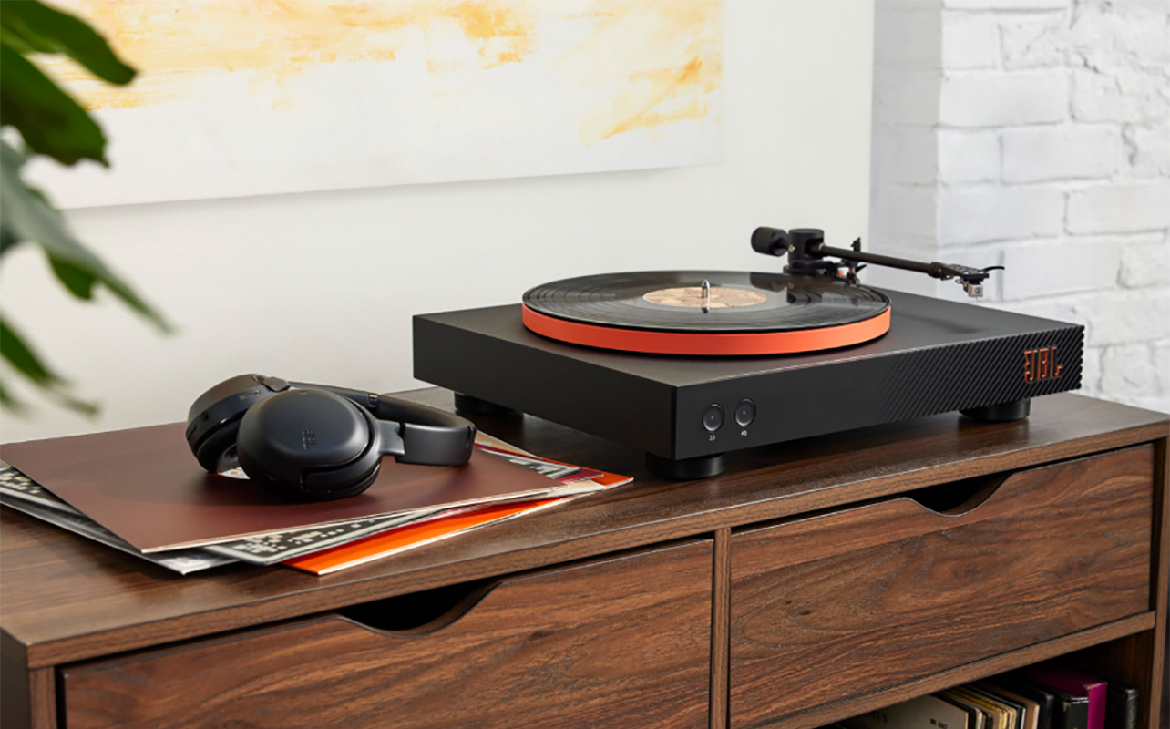 A JBL USB Bluetooth turntable on a buffet beside records.