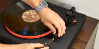 A man fiddling with the stylus on a JBL turntable.