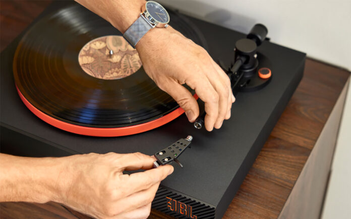 A man fiddling with the stylus on a JBL turntable.