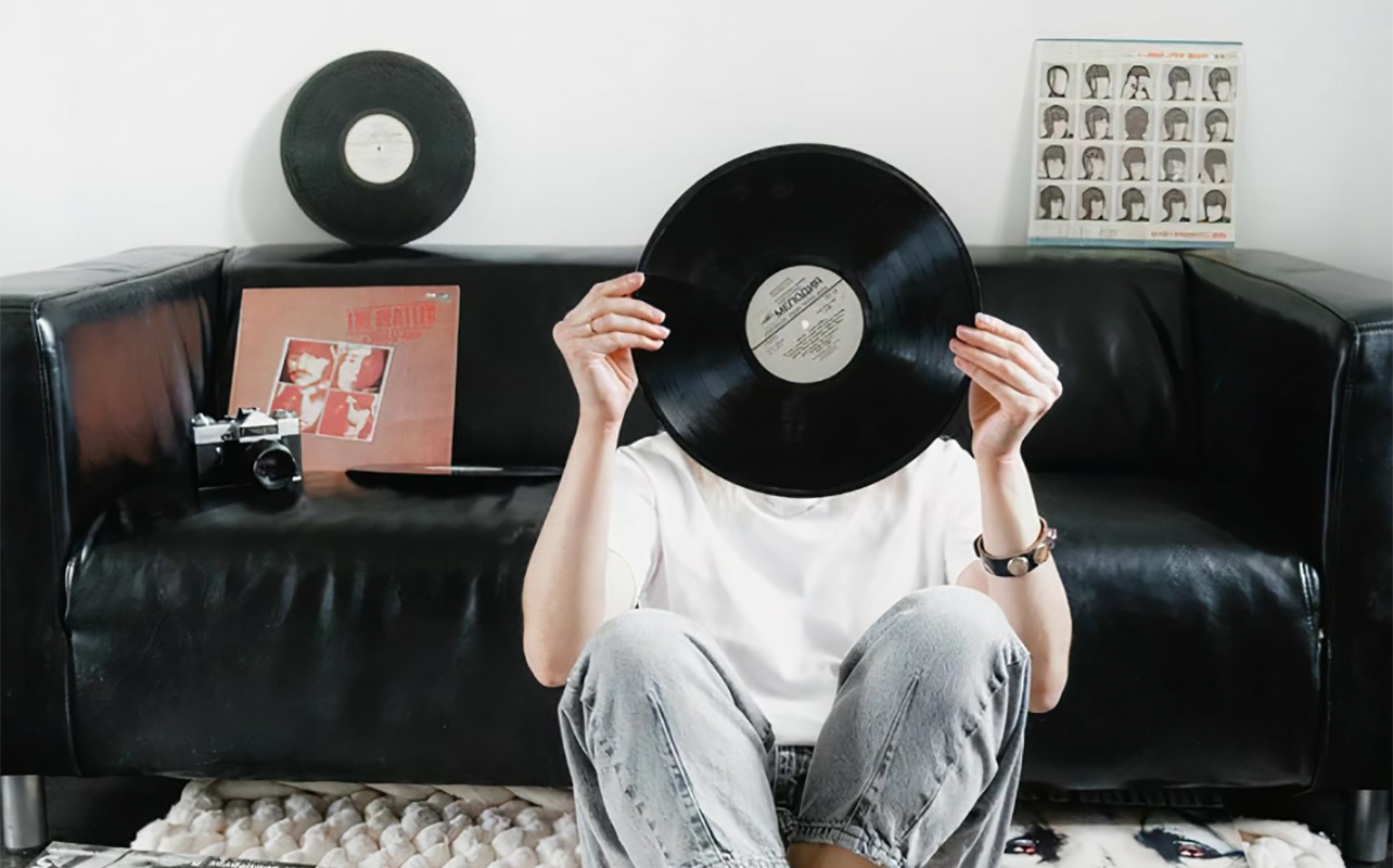 A woman holding a record over her face.