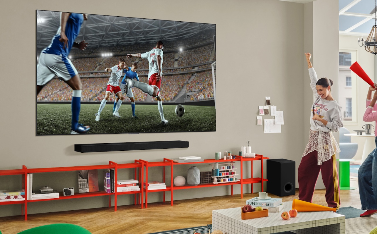 Viewers watch a soccer game on a wall-mounted OLED TV with sound bar