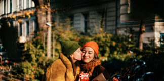 Woman kissing her girlfriend on a cheek on a street