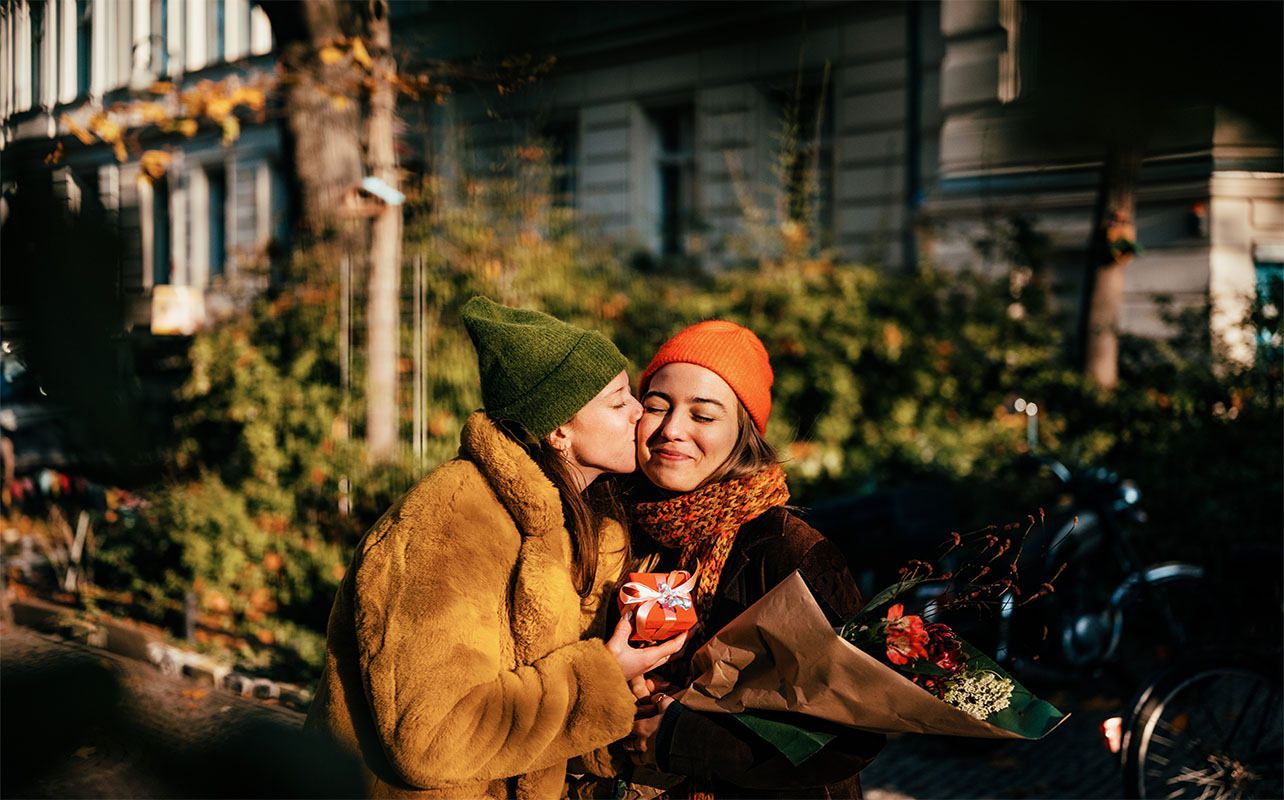 Woman kissing her girlfriend on a cheek on a street
