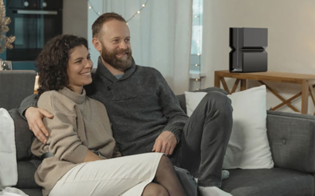 A couple watching TV with a TP-Link router in the background on a table.