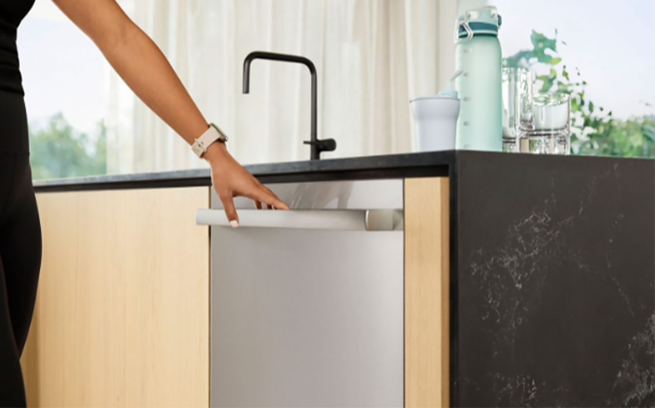 residential dishwasher with a person holding the handle
