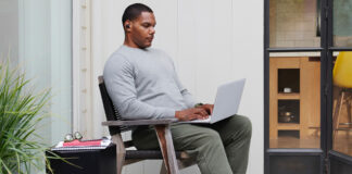 A man sitting back on his laptop.