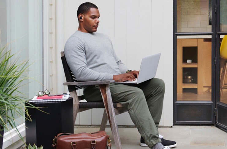 A man sitting back on his laptop.