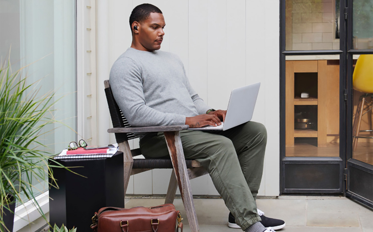 A man sitting back on his laptop.