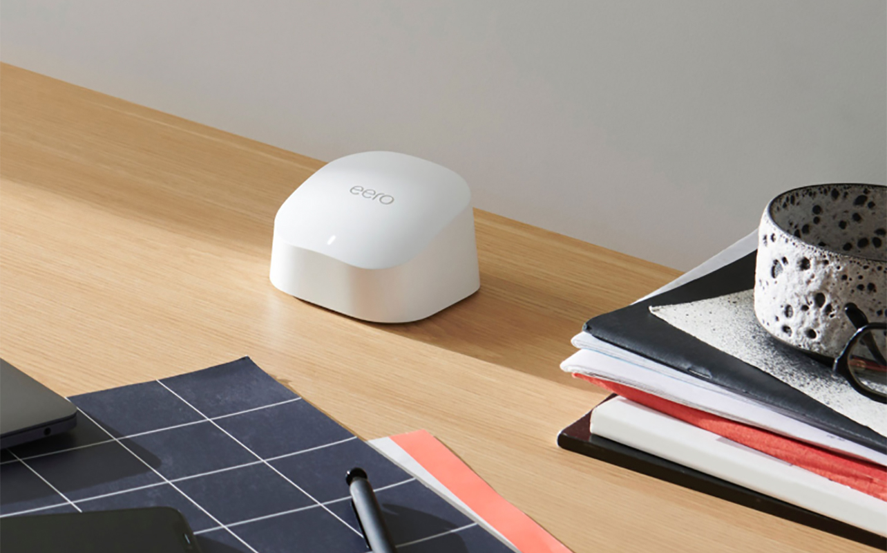 An Eero 6 mesh range extender on a desk with books.