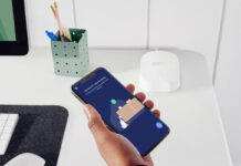 A hand holding a phone with the eero 6 mesh router app.