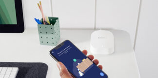 A hand holding a phone with the eero 6 mesh router app.