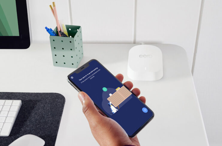 A hand holding a phone with the eero 6 mesh router app.