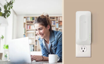 A woman on her laptop on the left and a Netgear AX3000 range extender mounted on the wall on the right.