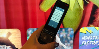 One For All Smart Pro Touch remote in front of a TV.