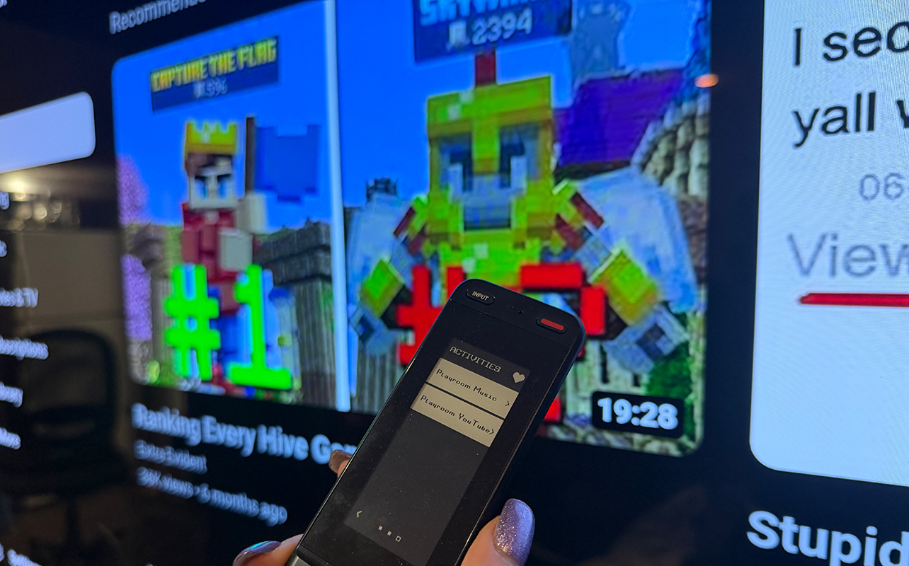 The One For All Smart Touch Pro remote in front  of a TV showing YouTube.