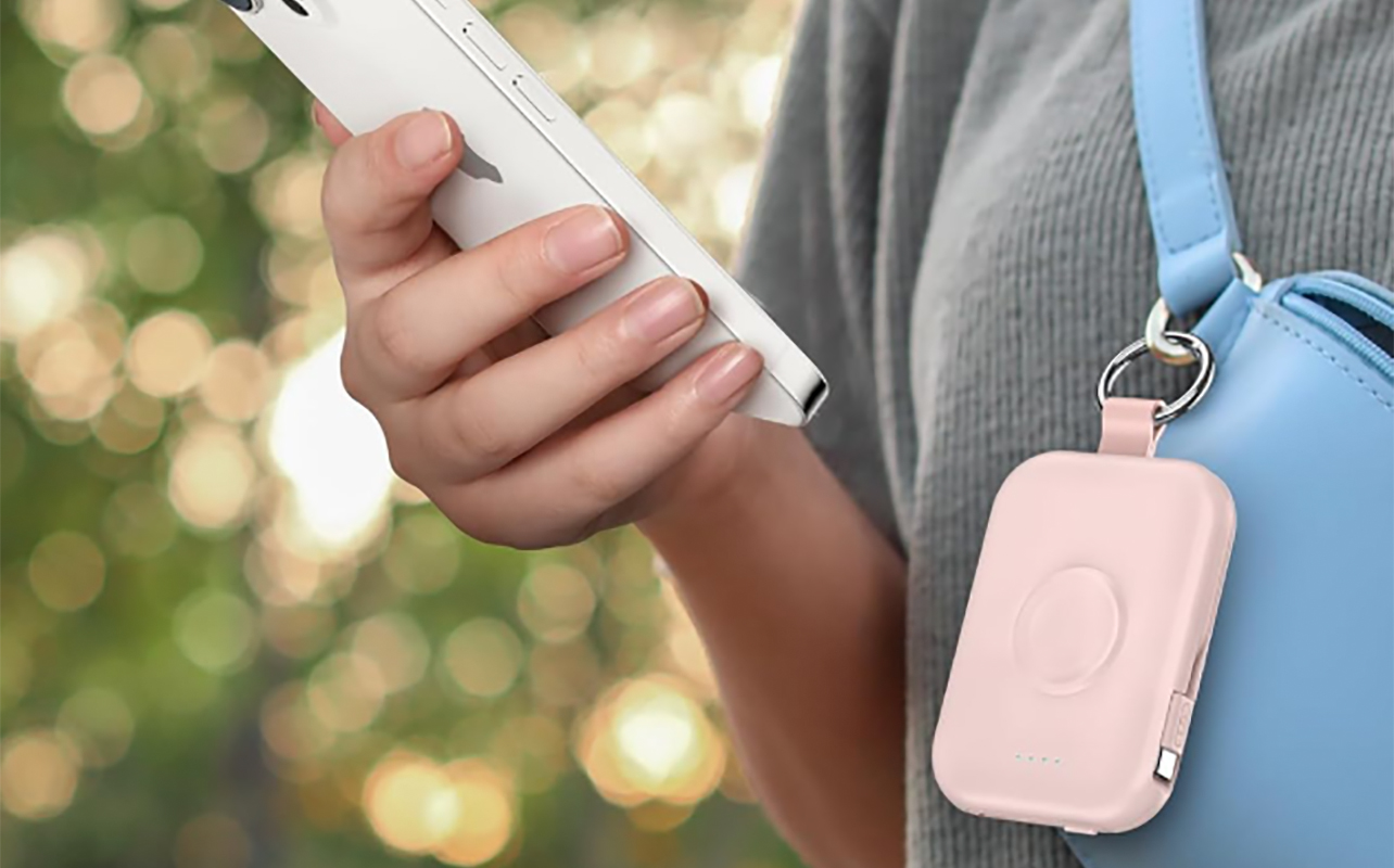 A woman wearing the Rory 5,000mAh power bank clipped to a belt bag while holding a phone.
