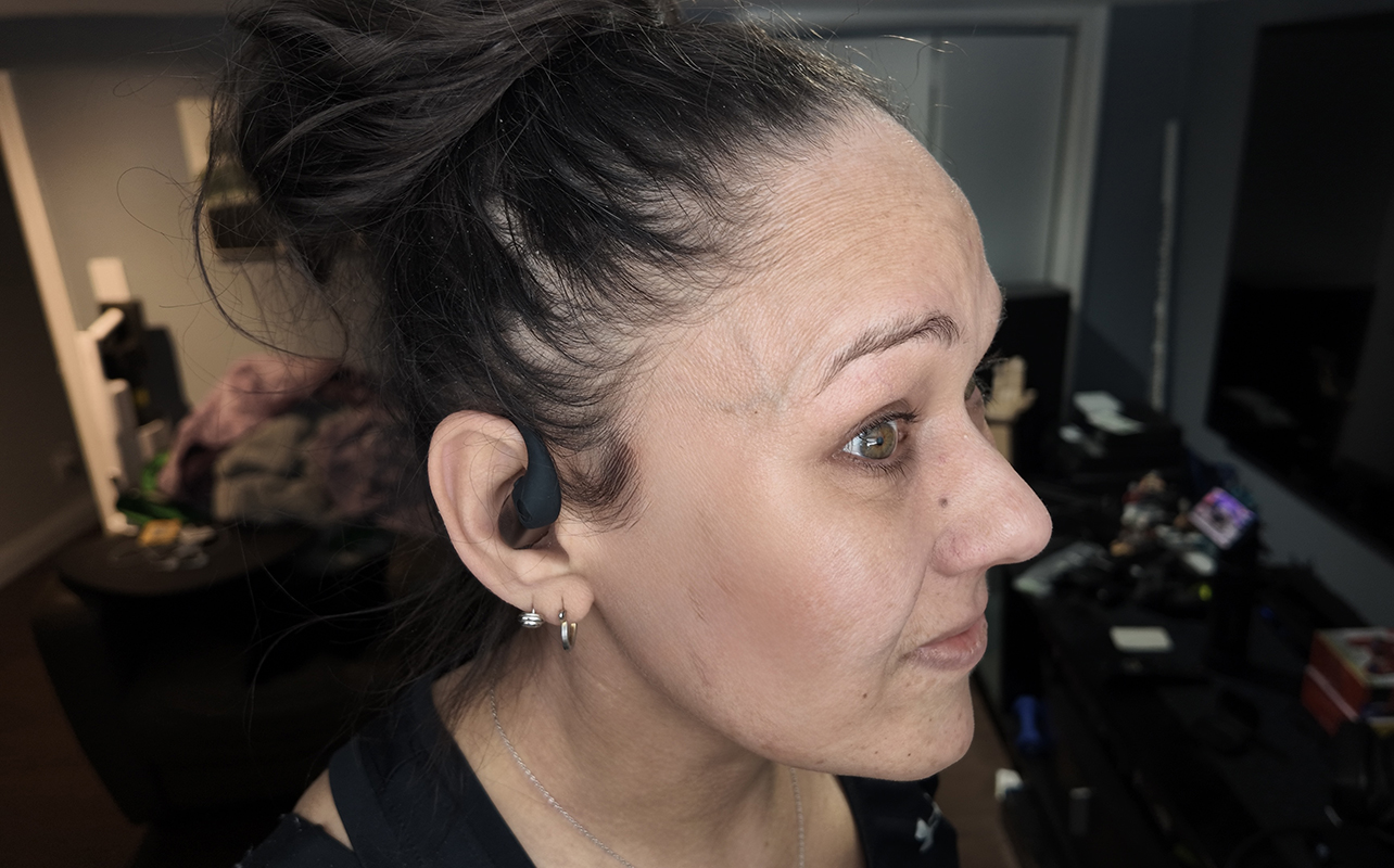 A woman wearing the Shokz OpenFit Pro earbuds