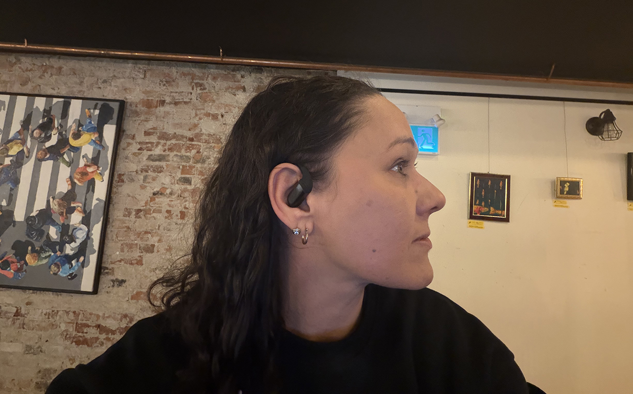 A woman wearing the Shokz OpenFit Pro earbuds.