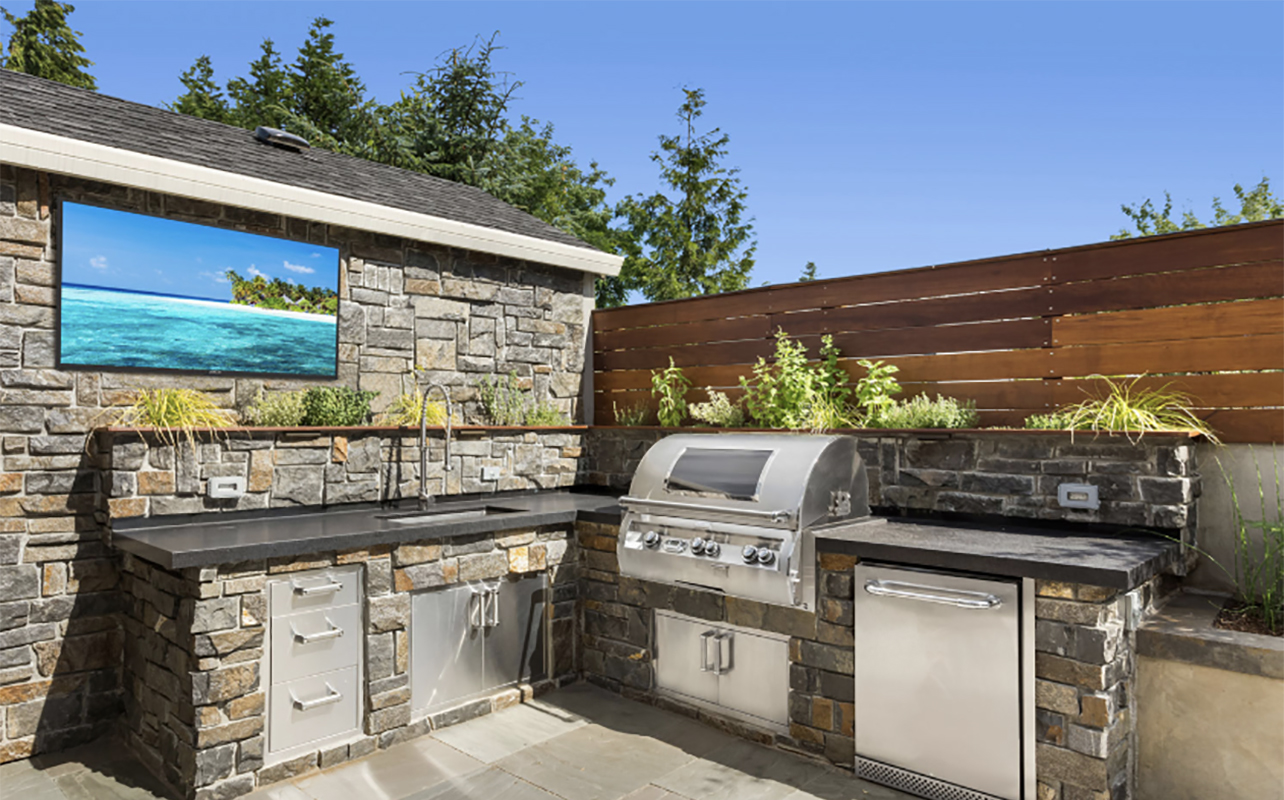A Neptune Full Sun outdoor TV beside a barbecue.
