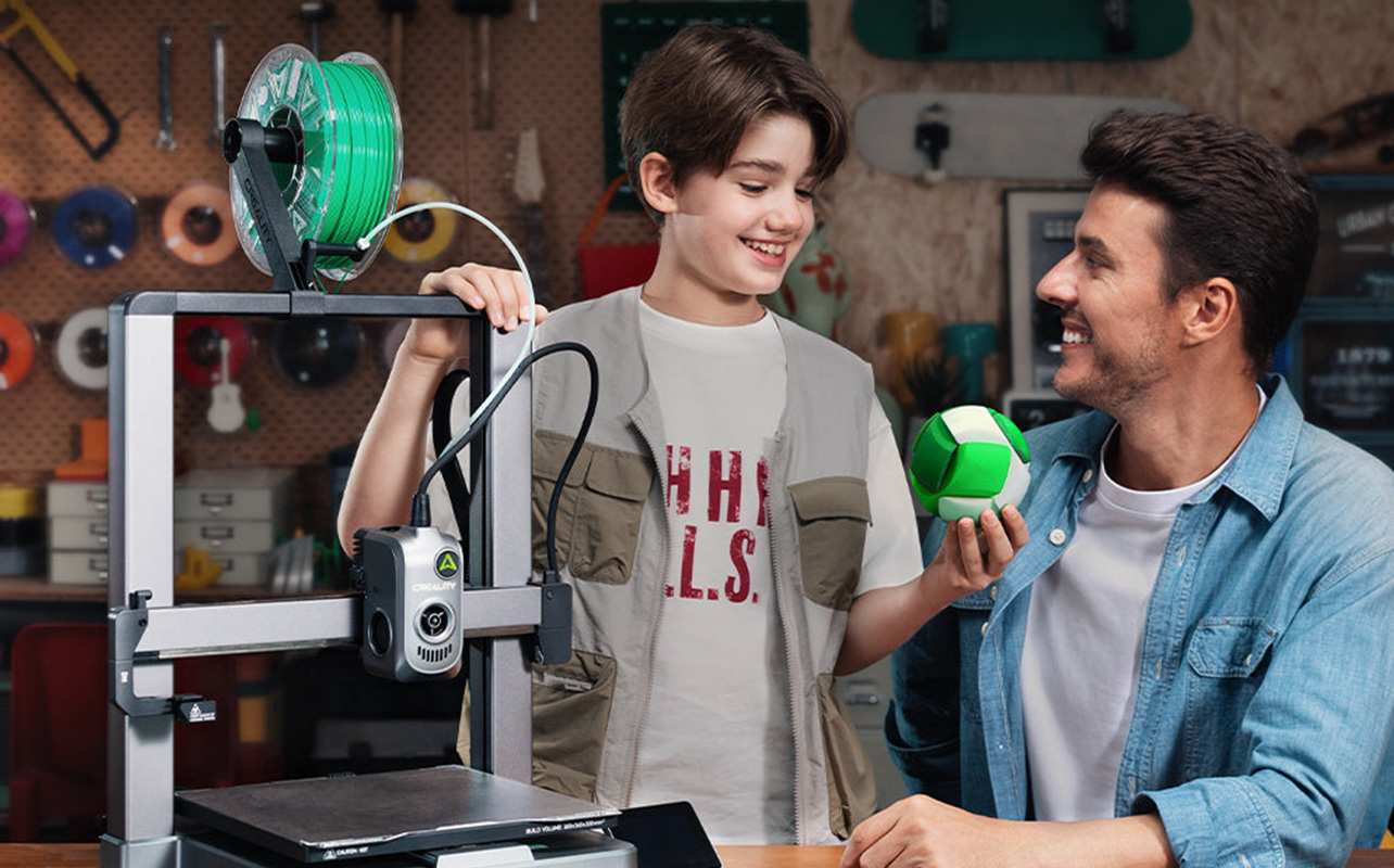 A child and father loading green filament into a Creality 3D printer 