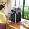 Woman using a 3D printer on a table at home.