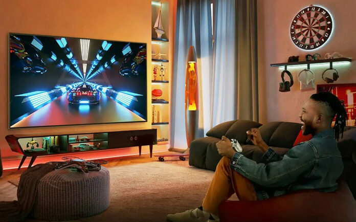 A man sitting on a couch playing games on a TV.
