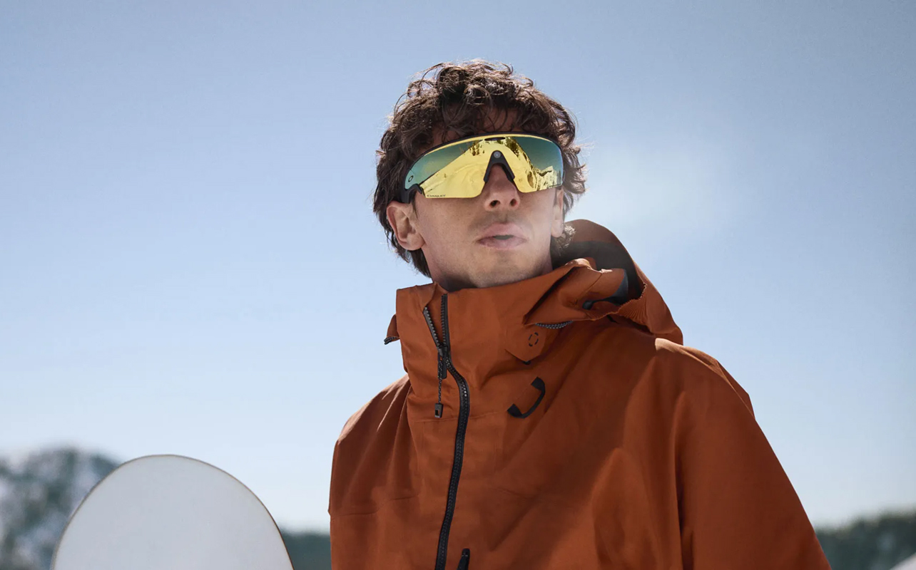 Man wearing Oakley Meta Vanguard AI glasses snowboarding.