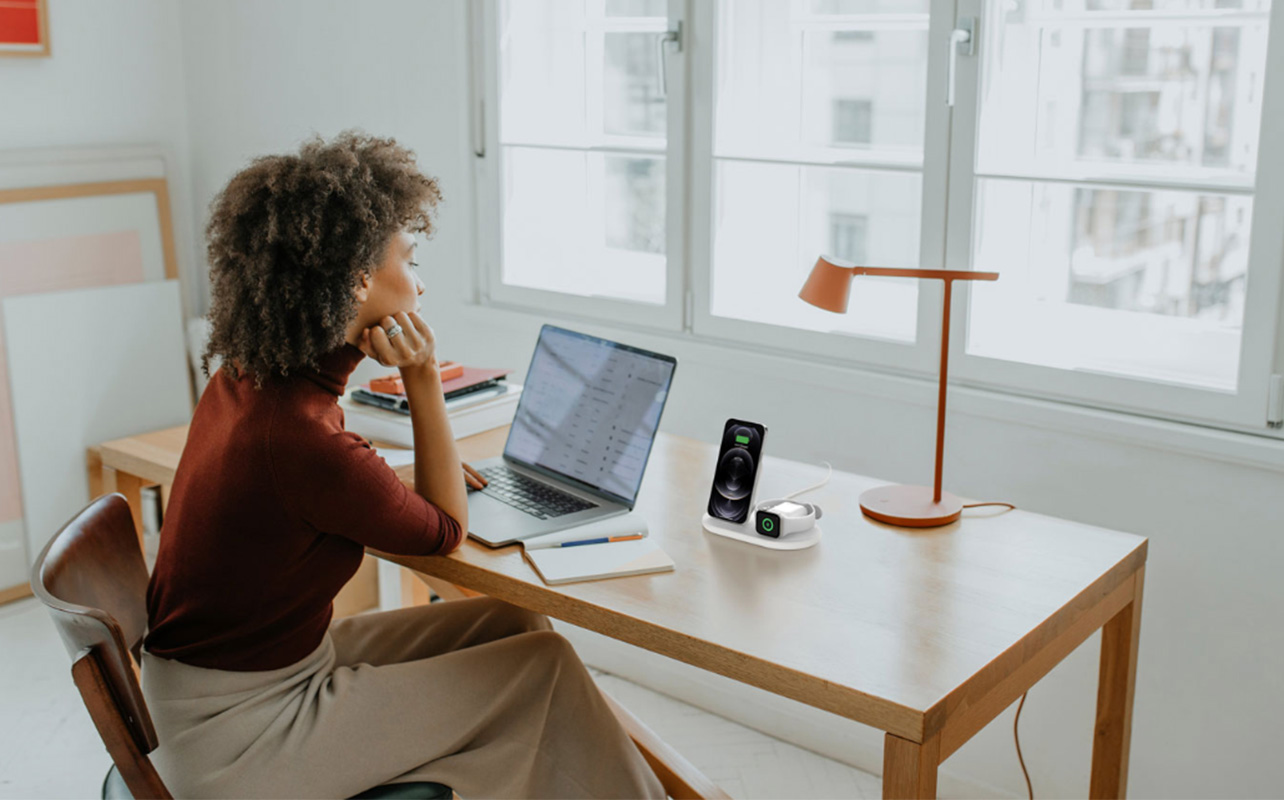 Woman working on laptop and charging phone and apple watch