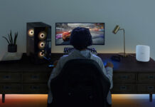 The back of a man playing video games at a computer desk with the Eero Max 7 Wi-Fi mesh system.