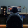 The back of a man playing video games at a computer desk with the Eero Max 7 Wi-Fi mesh system.