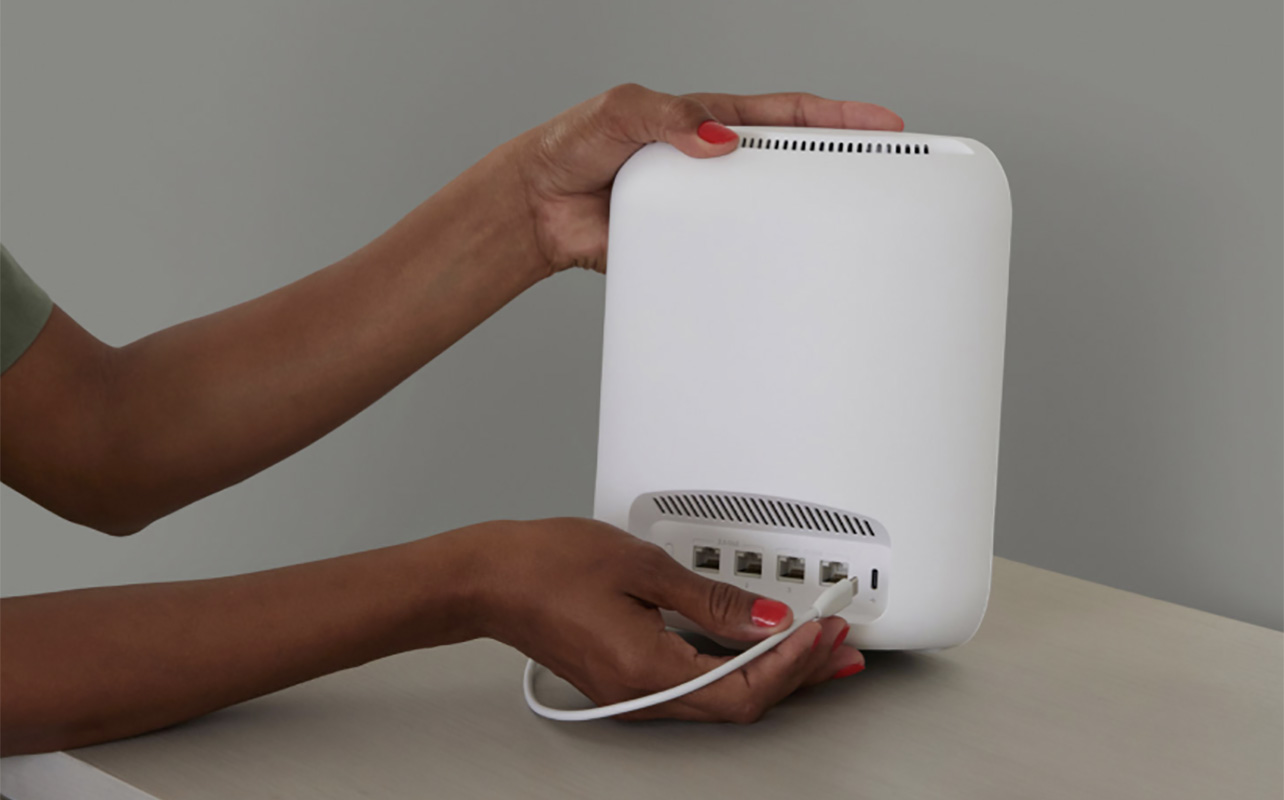 A hand plugging in an eero Max 7 Wi-Fi mesh system