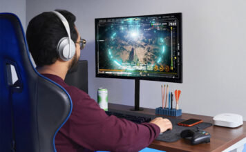 Do you really need the fastest internet speed available? A man sitting at a desk playing games on a computer with an eero Pro 6 mesh Wi-Fi node beside him.