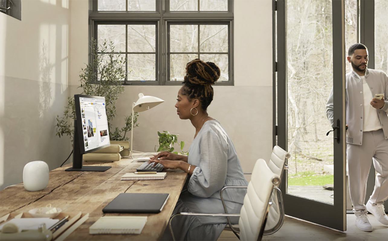 A woman at her desk with a Google Nest Wi-Fi Pro node on it.