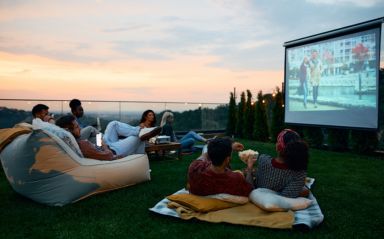 Friends watch a movie outdoor using a projector