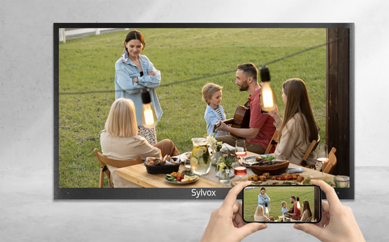 A Sylvox outdoor TV with a hand holding a phone in front of it.