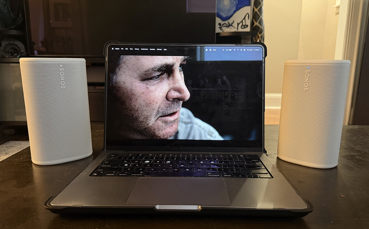Two Sonos Play speakers on either side of a MacBook Pro on a table.