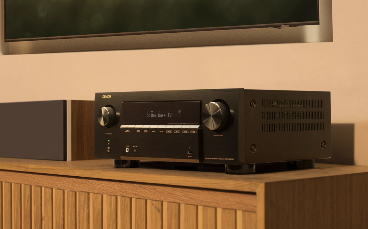 Close-up of a Denon receiver on a piece of furniture.