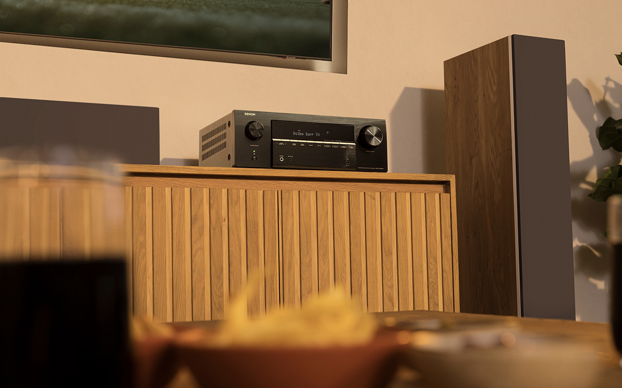 A Denon AVRX2900 AV receiver on a piece of furniture.