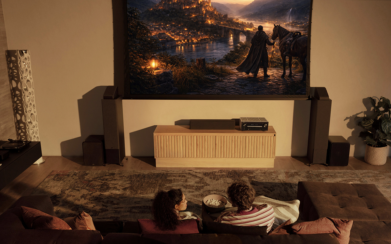 A couple watching TV with an AV receiver under it. 