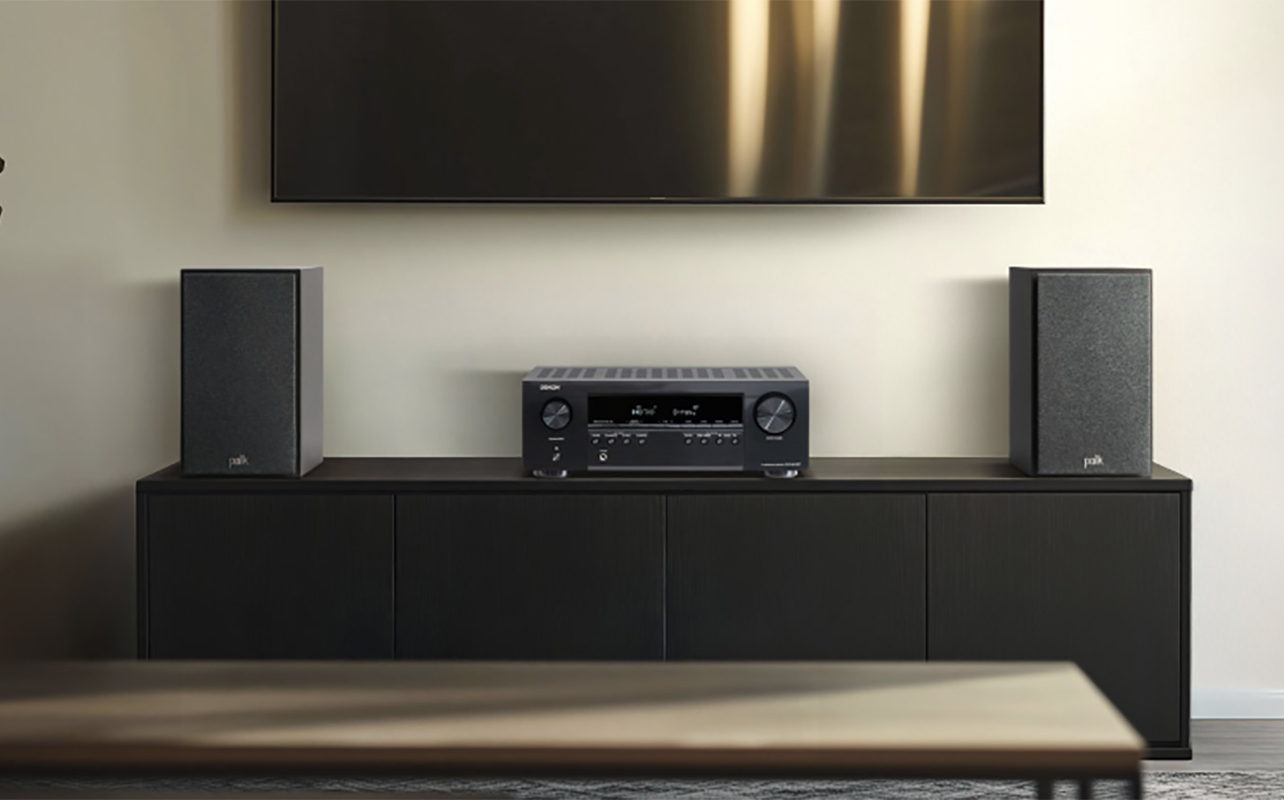 A Denon S270BT AV receiver on furniture with two bookshelf speakers on either side.