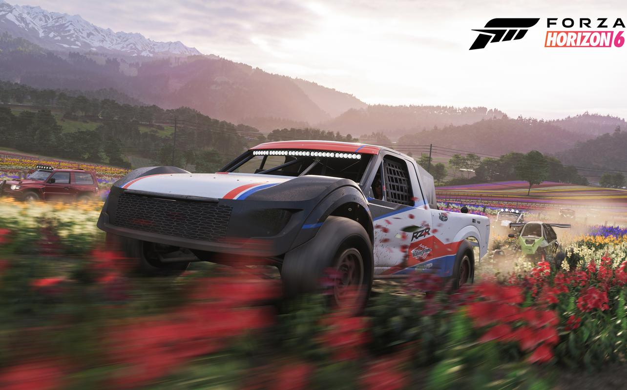 A white and red off-road racing truck drives through a field of red flowers in the Japanese countryside in Forza Horizon 6.