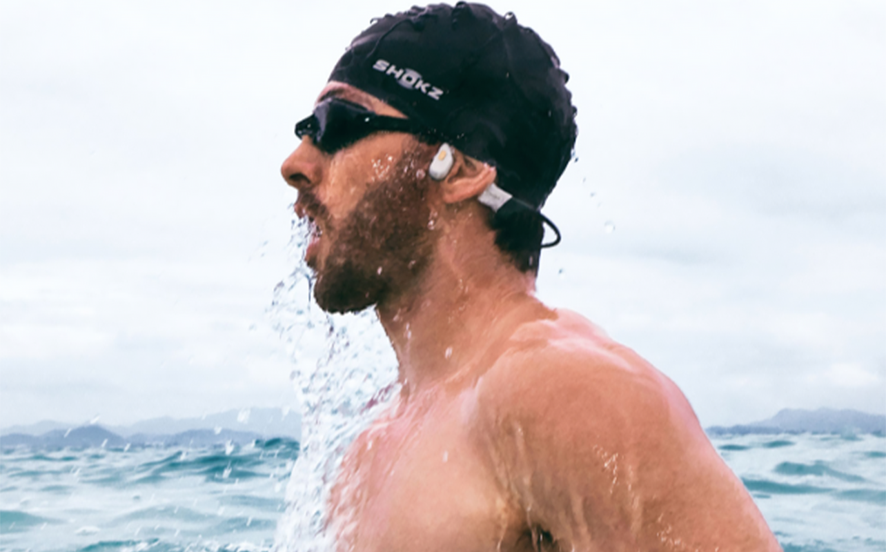 a swimmer wears a pair of open-ear headphones