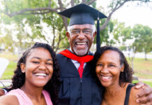 A senior man graduates with his master's degree and takes a photo with his family