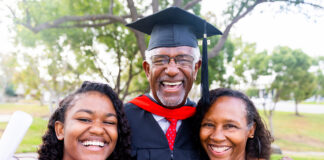 A senior man graduates with his master's degree and takes a photo with his family