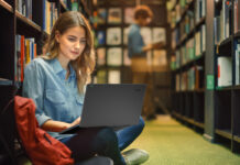 Young student in library using a laptop.