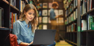 Young student in library using a laptop.
